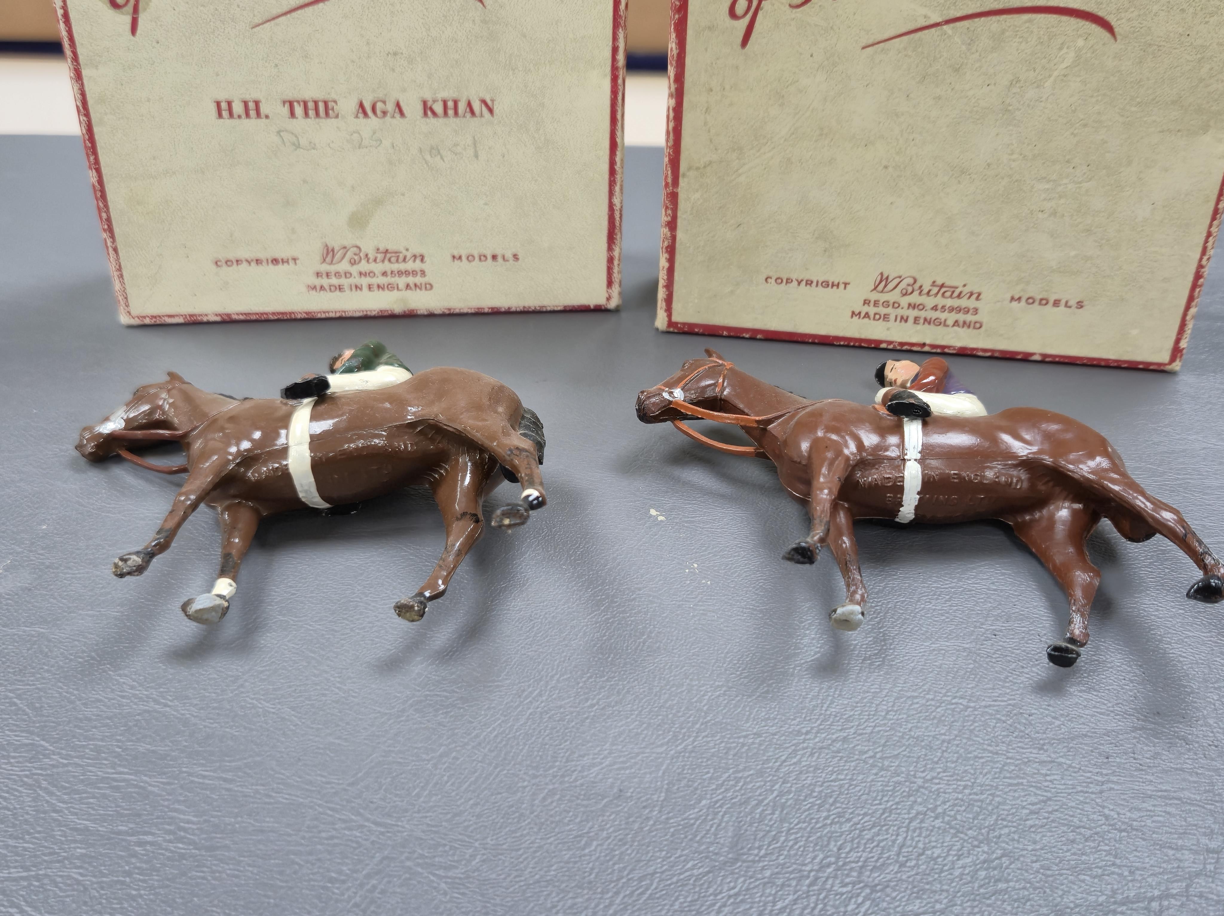 Two boxed Britains Racing Colours of Famous Owners series lead mounted figures; H.M. The Queen - rider in purple and brown jersey with gold frogging on a brown horse, and H.H. The Aga Khan - rider in dark green jersey on